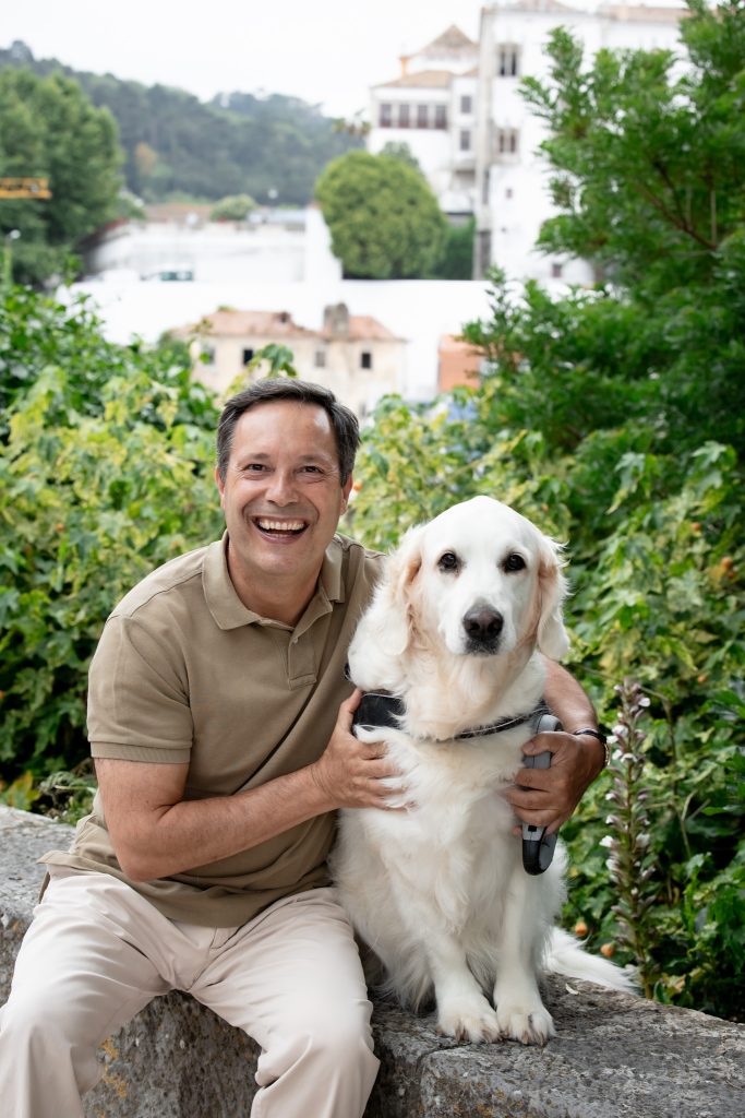 Mário Tavares da Silva sorridente ao lado da sua cadela golden retriever Ginja, em Sintra